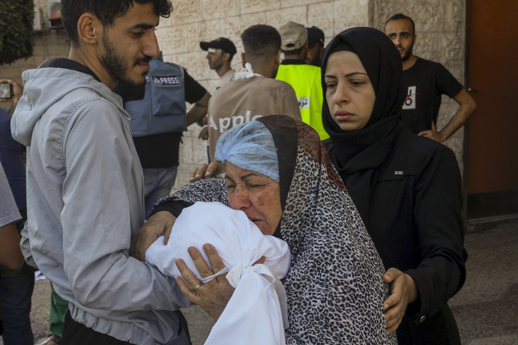 加沙醫院外有婦人親吻在空襲中死亡的孩子。美聯社