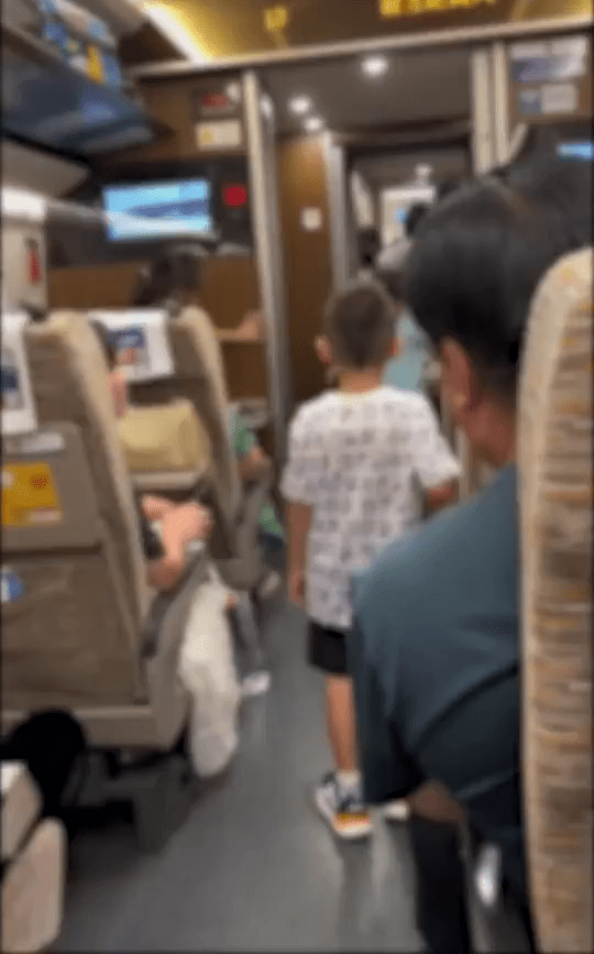 網片顯示，兩名小孩在高鐵車廂走廊玩耍踢波。