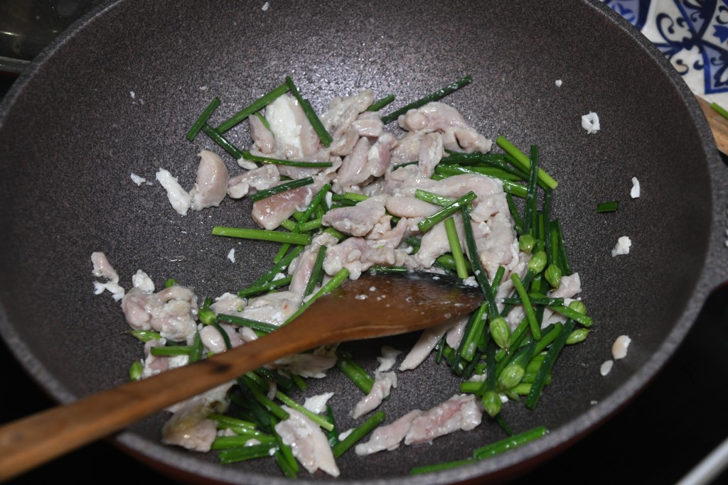 Step 6: 加入韭菜花快手煸炒。Add the leek flowers and toss quickly.