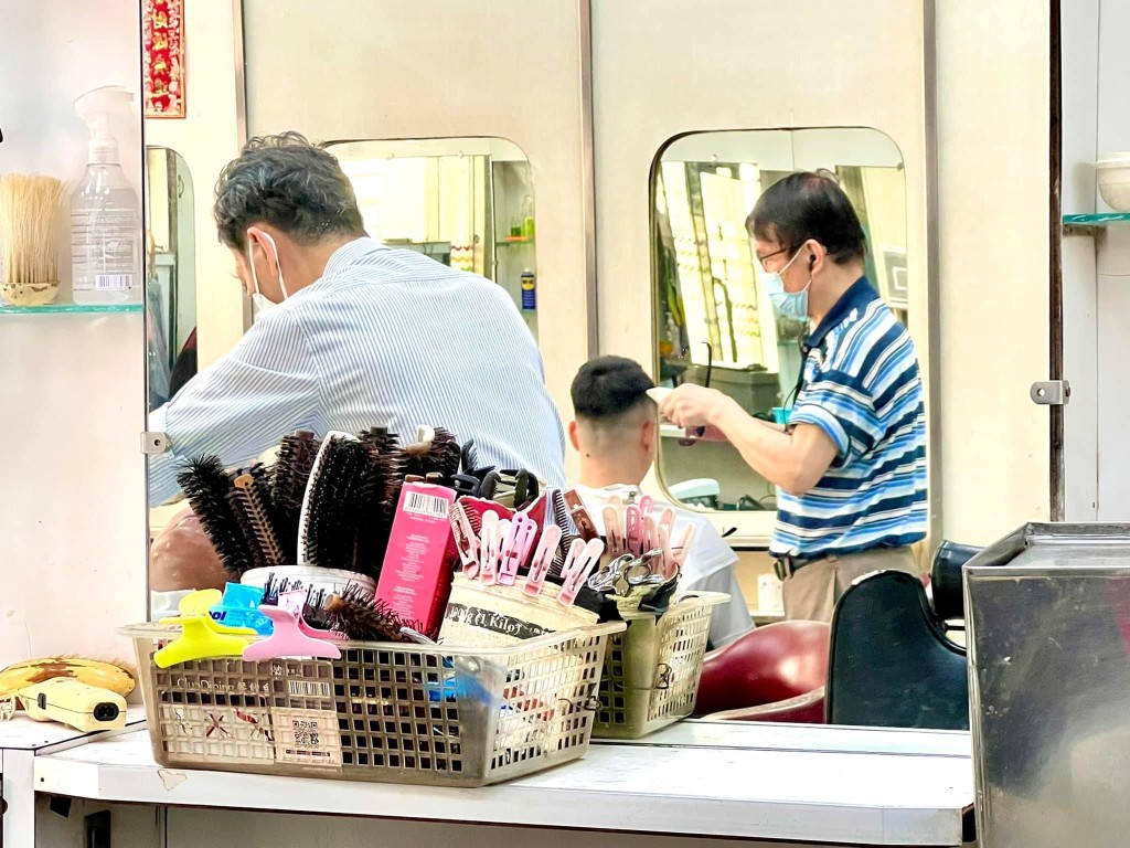 理发厅师傅替客人理发。上海华丽理发公司 Facebook图片