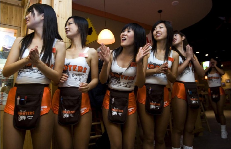 Hooters北京分店的女侍身穿紧身低胸白背心、橙色热裤制服招呼客人。 美联社 Hooters北京分店的女侍身穿紧身低胸白背心、橙色热裤制服招呼客人。 美联社