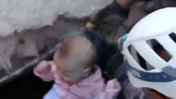 救援人員從大樓瓦礫中抱出女嬰。網上影片截圖