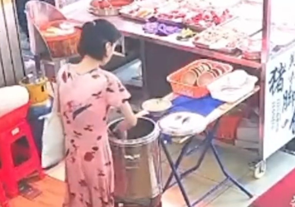 女子将碗内的不明物体倒入大锅食物中。