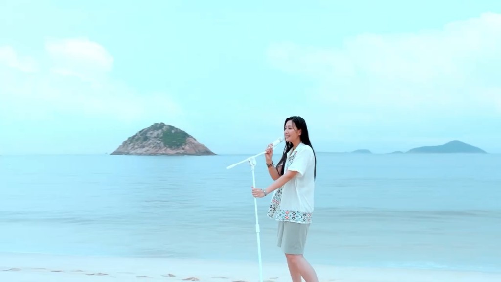 谭旻萱在海边唱歌。
