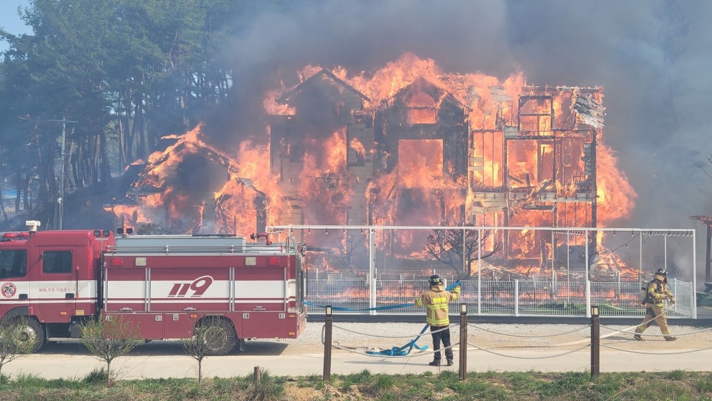 江陵市山林大火，一座建築物燒通頂。消防人員試圖控制火勢。 路透社
