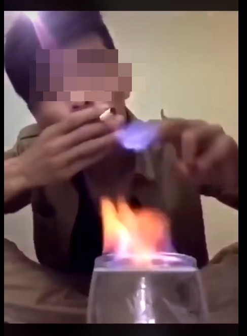 一名型男对著镜头示范徒手以手指捞起火焰酒的火种点烟。网上截图