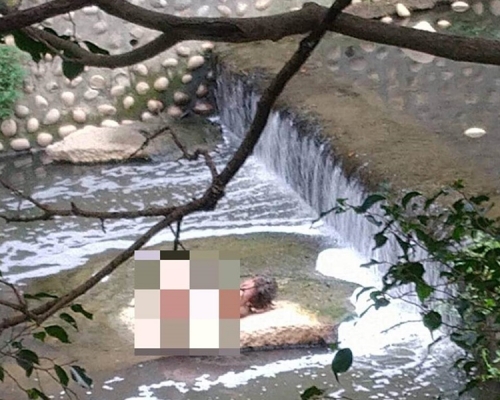 男子一絲不掛躺在排水溝的大石上。中時