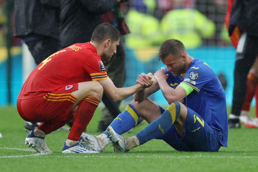 威尔斯(红衫)球员安慰乌克兰(蓝衫)球员。Reuters