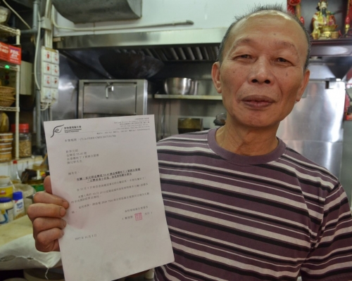 店主陳先生展示食環署 還他清白的報告。