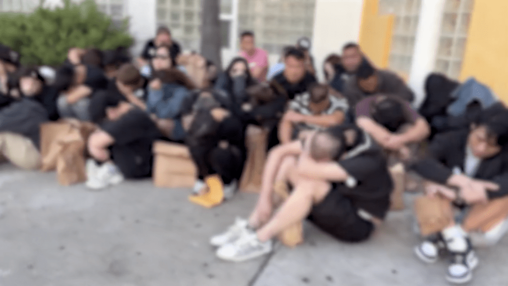 多名被捕人士低著頭,坐在行人路上。@HSILosAngeles / X