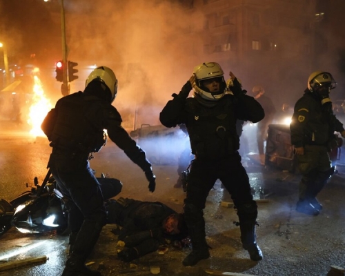 希臘爆發警民衝突，有警員在衝突現場幫助倒到受傷的同袍。AP圖