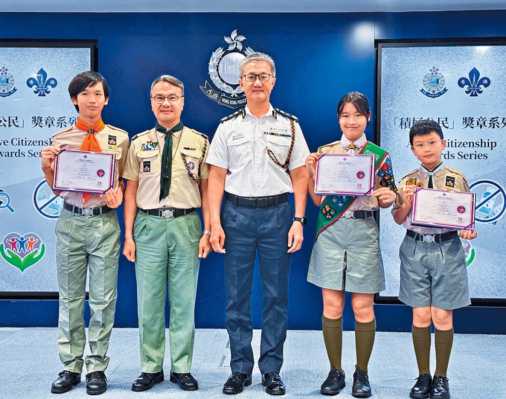 警務處處長蕭澤頤(中)、香港童軍總會香港總監黎偉生(左二)與3名完成「防騙先鋒章」的童軍成員黃晉軒(左一)、黃樂晴(右二)、梁桀朗(右一)留影。 