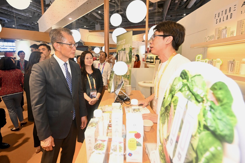 陈茂波在进博会到访香港的参展商展位，听取参展商介绍产品。政府新闻处  ​