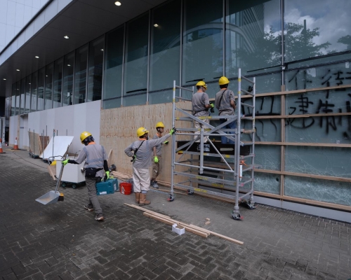 工人以木板圍封被打爆及塗鴉的玻璃，進行維修。