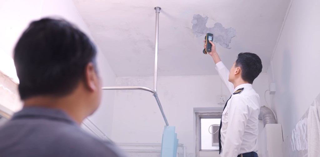 聯辦處職員使用電子濕度儀量度天花滲水位置的濕度值。食環署提供