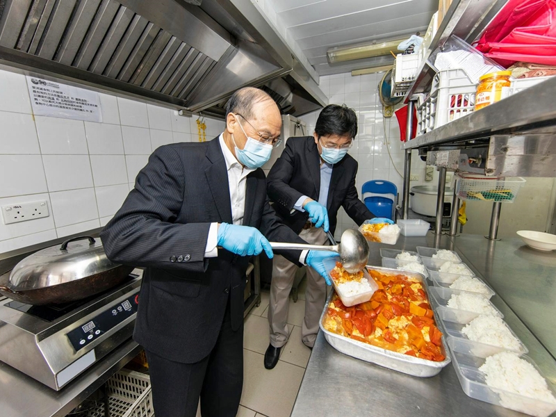 尹志田（左）與聖巴拿巴會之家主席敖卓絢（右）為西環區的基層人士預備免費飯盒。