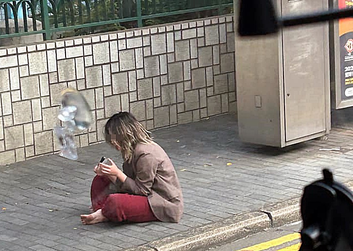 女子坐在巴士站對開。fb：馬路的事討論區