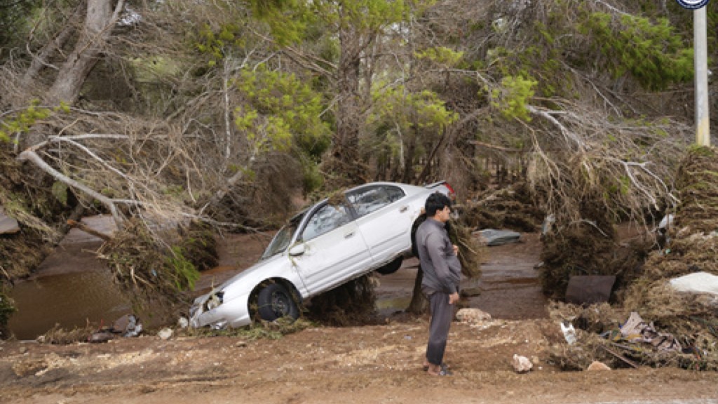 利比亚发生毁灭性的洪灾，一辆汽车被水冲走后搁在倒地的树干上。 美联社