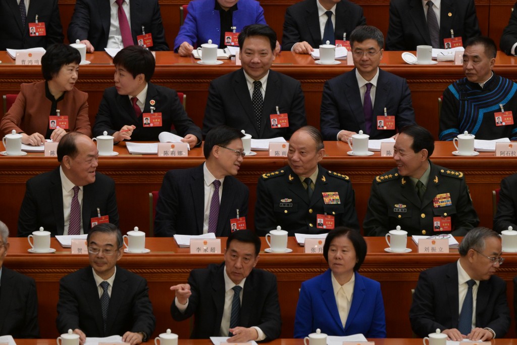 坐下之後分別與坐其左手旁的中央軍委委員張升民及劉振立握手，雙方交談甚歡。蘇正謙攝