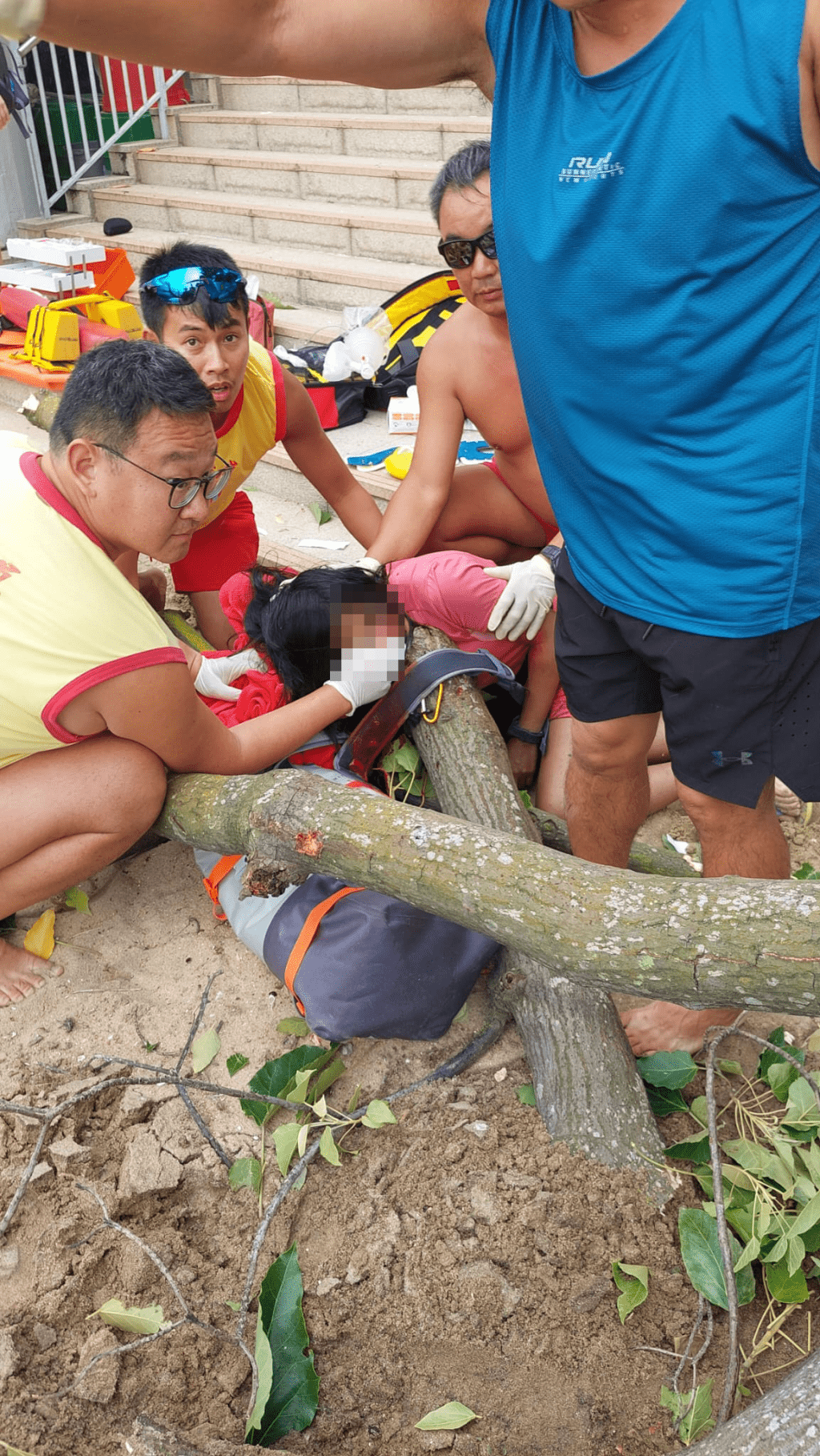 女子被塌下的树干击中，在场救生员立即上前协助。