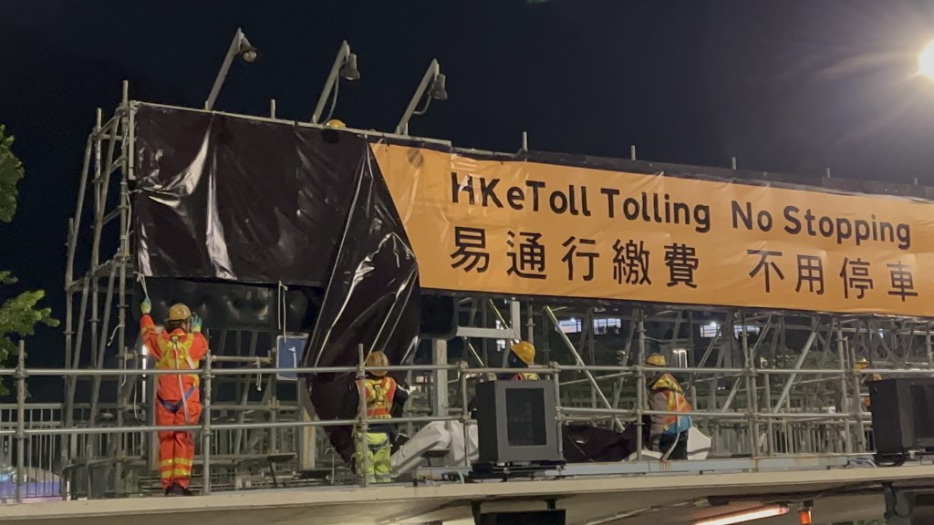 工作人員在香港仔隧道收費上方裝上「易通行繳費 不用停車」的大型提示牌。