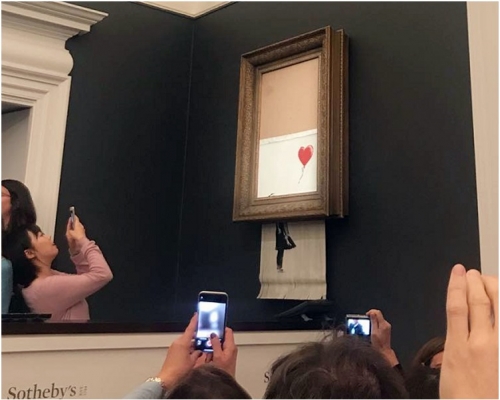 作品在众目睽睽下，被画框内藏的碎纸机碎成条状。网图