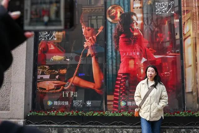 2024年1月7日，上海，游客在和平饭店门前的《繁花》剧照前合影。澎湃新闻