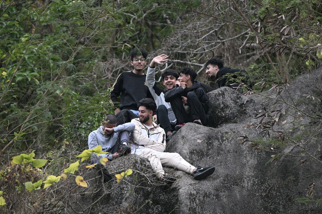 6名南亚裔青年为一睹美斯球技，竟冒险爬上大球场旁边的山坡坐「山顶位」。苏正谦摄