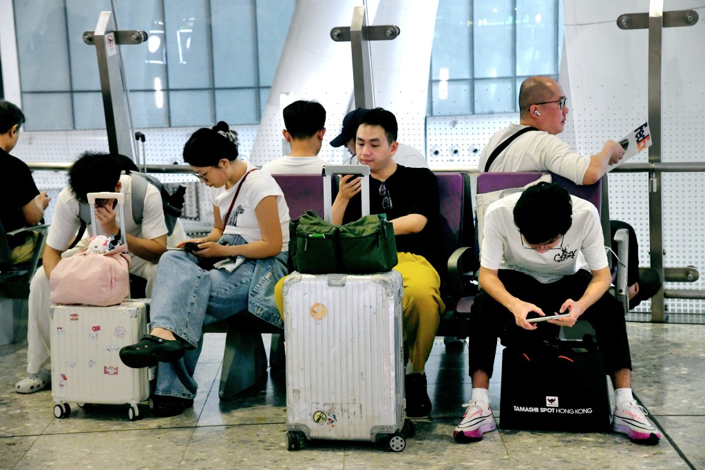 大批拖着行李箱的旅客離港。何健勇攝 大批拖着行李箱的旅客離港。何健勇攝