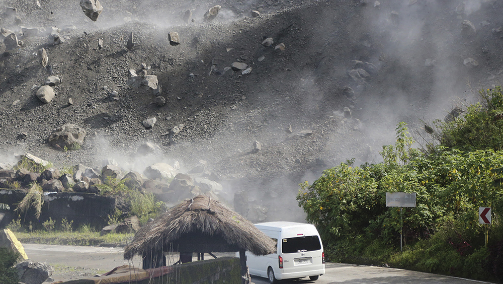 地震發生後，一輛汽車在道路上行駛時，遇上巨石墜落。AP