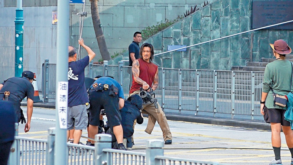 手持重型武器的霆鋒,在中環街頭上映一幕槍戰。