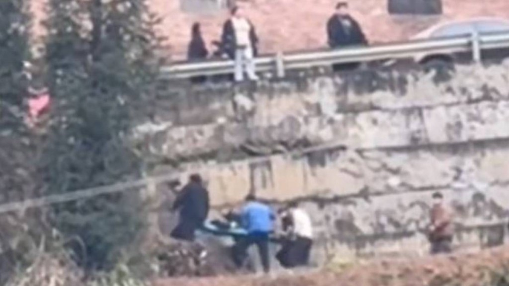 救援人員用擔架將墜崖消防員抬走。極目新聞