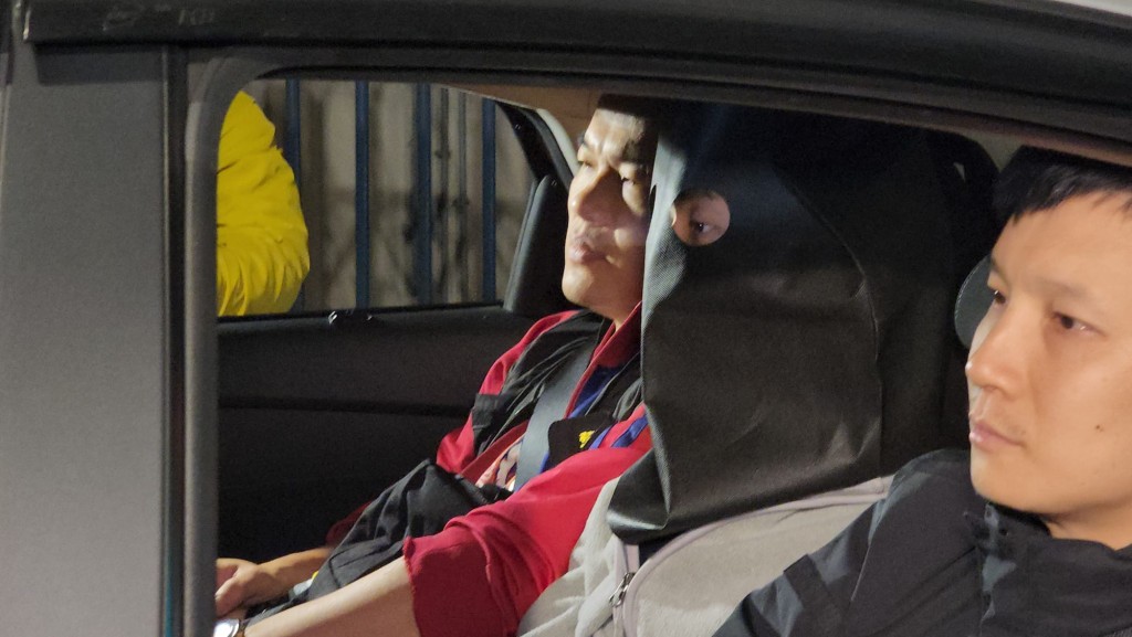 24日凌晨零時左右，其中一名被捕男子被帶上頭套，在重案組人員押解下，由便裝警車載離田心警署。黎志偉攝