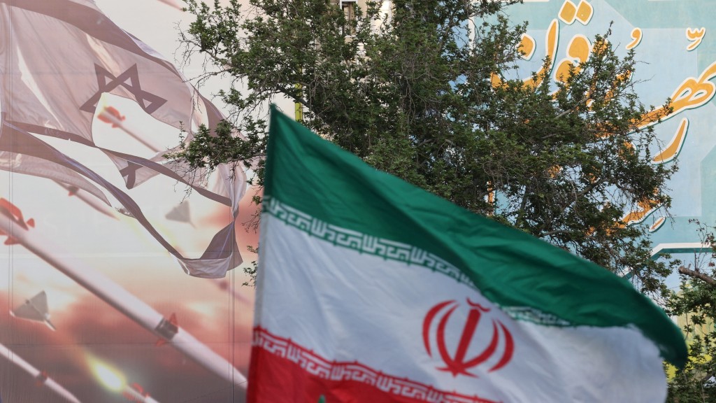 伊斯蘭革命衛隊攻擊以色列後，人們上街慶祝，在巨型反以壁畫旁揮舞伊朗國旗。路透社