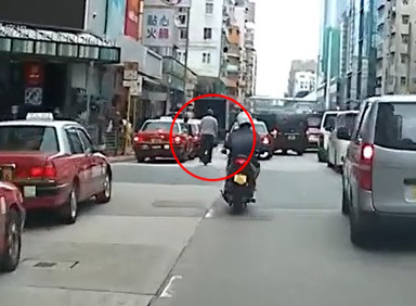 一名男子乘「风火轮」在马路上奔驰，慢慢接近一架的士。