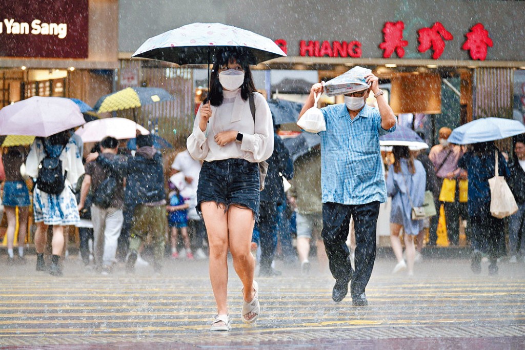 全港多區下大雨,有市民臨急以報紙擋雨。