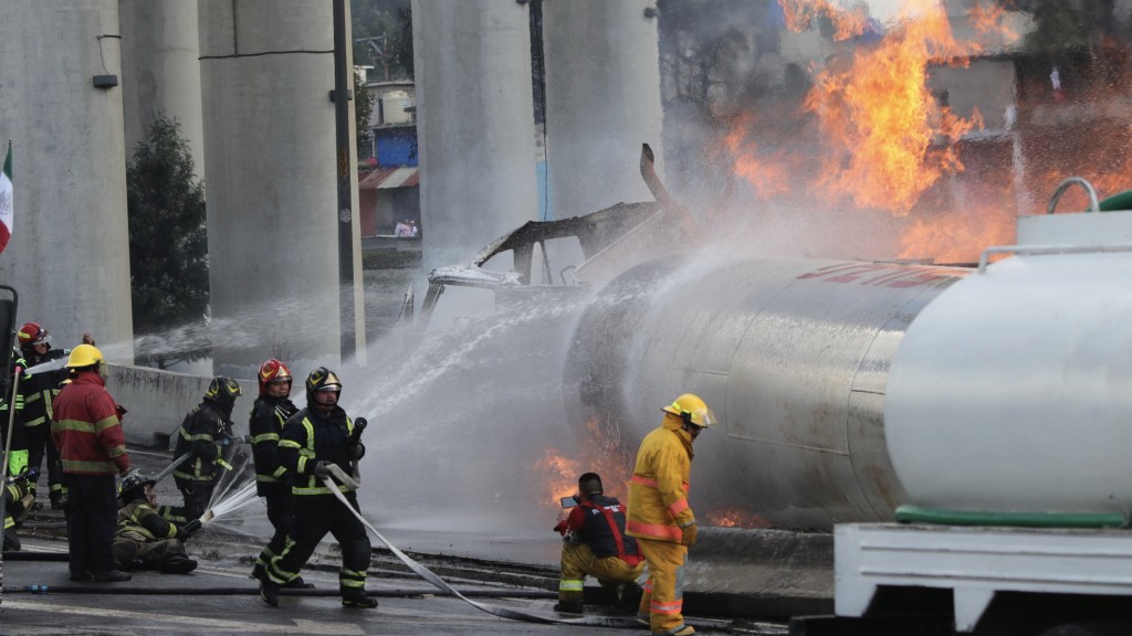 墨西哥氣罐車翻側爆炸，消防員向肇事氣罐射水。 美聯社