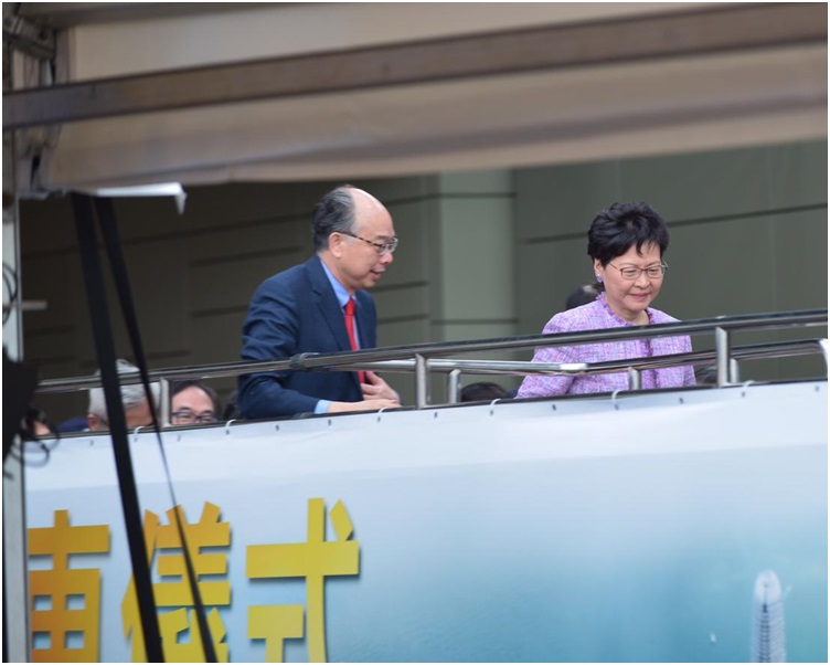 林鄭月娥(右)與陳帆等嘉賓,乘開篷巴士經繞道到中環出入口主持儀式。