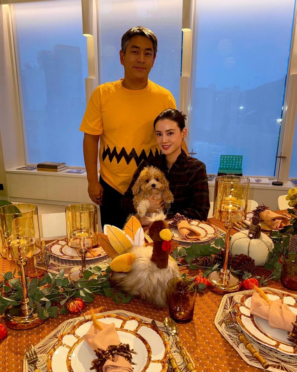 盤起頭髮的林恬兒身穿格仔圖案襯衫配黑色長褲，抱着愛犬與老公及兩個仔女在餐桌前留影。