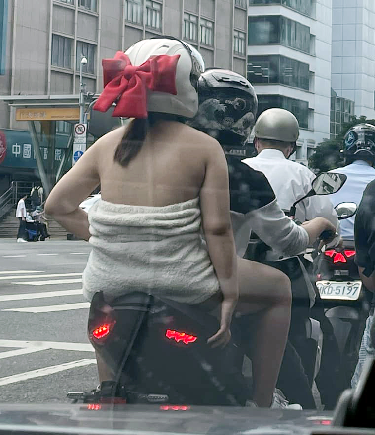 這位馬尾妹只包著浴巾坐在電單車後座等紅燈，大膽衣著相當觸目。
