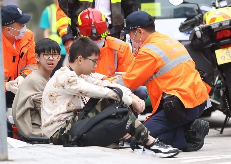 受伤少年巴士迷（左二）坐在地上接受初步敷治。fb：Justin Cheung