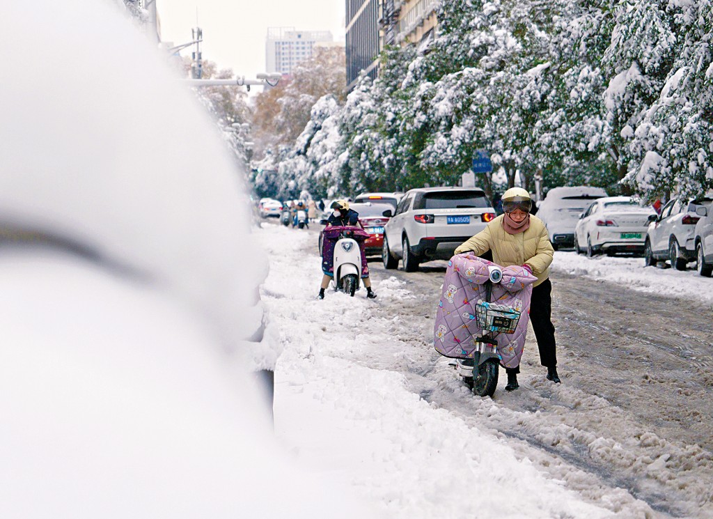 鄭州市民在雪地裏推車前行。