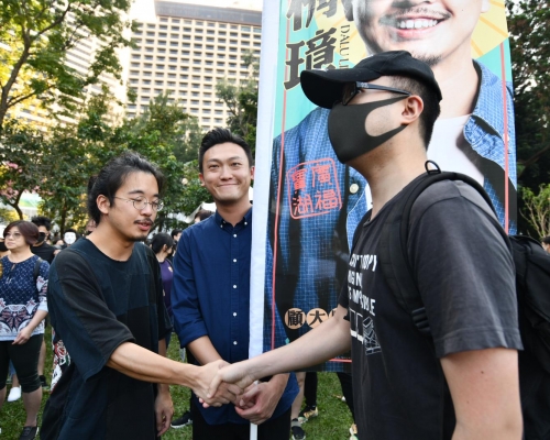 候选人高举选举旗帜与在场人士交流。
