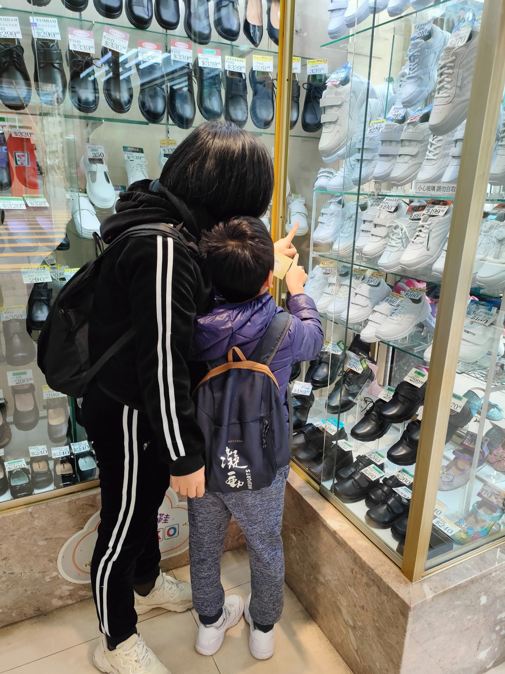 浩仔媽媽領鞋券後帶着兒子揀選其心儀的波鞋。(莫家文攝)