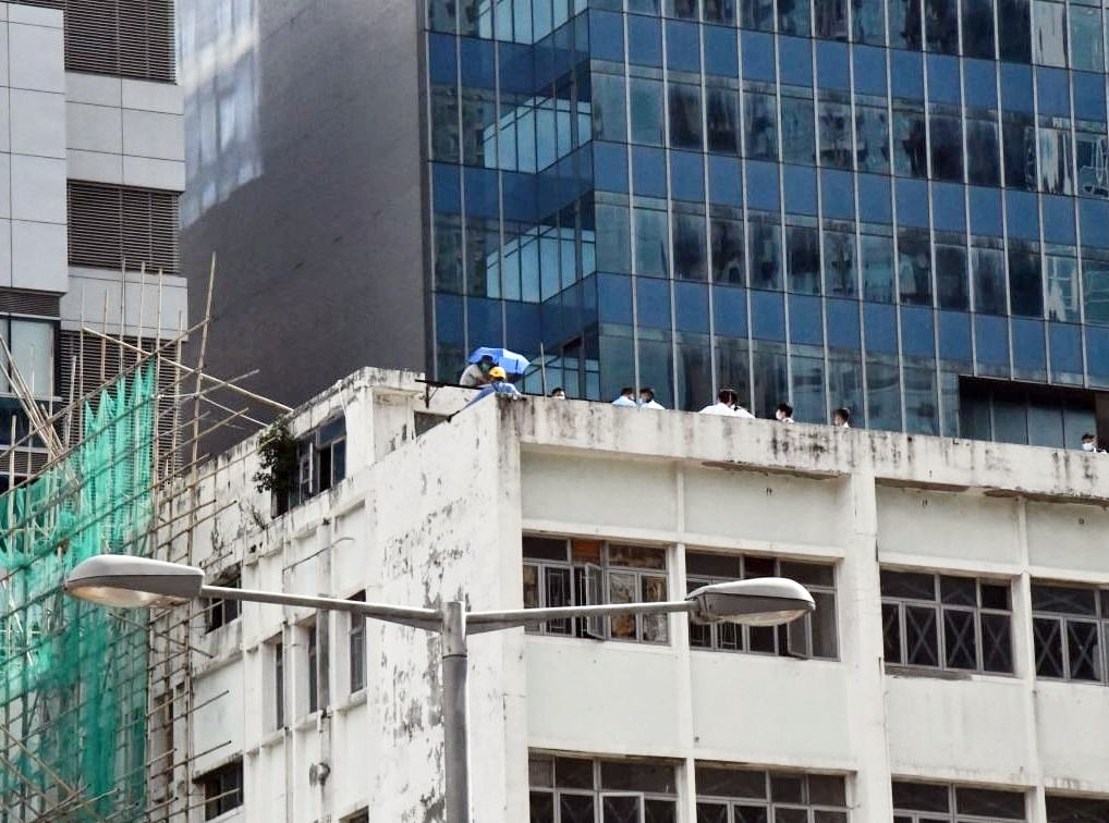 男子持傘危站大廈天台。