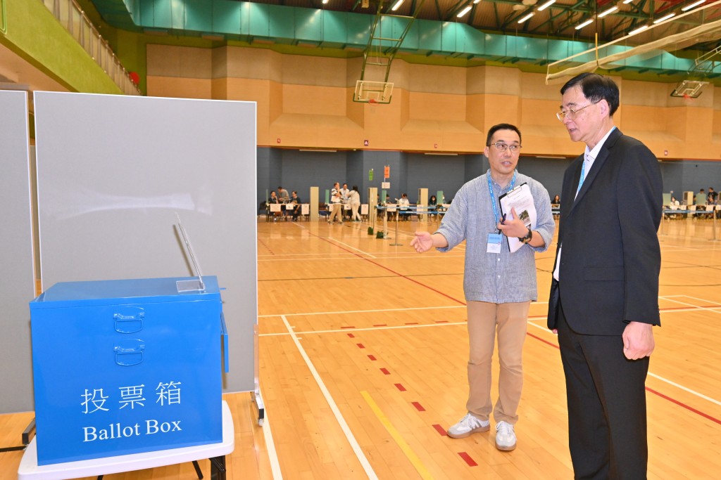 石丹理（右）巡視設於蕙荃體育館的2025年選舉委員會界別分組補選投票站，實地視察投票站人員的預備工作。政府新聞處