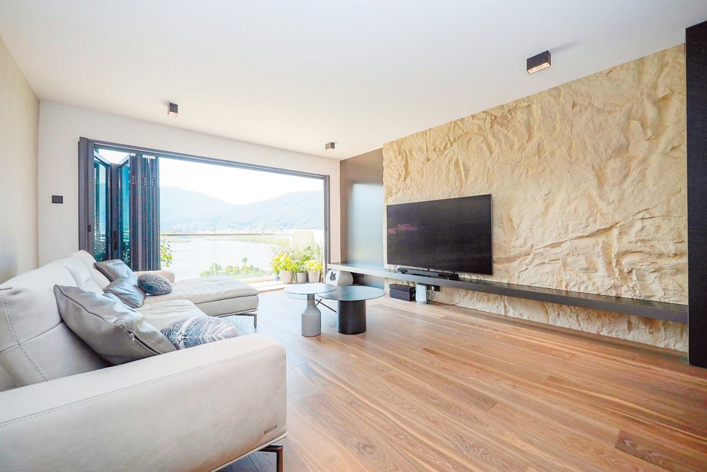 客廳電視牆面以山岩石設計，配合戶外山海景致，營造度假氛圍。