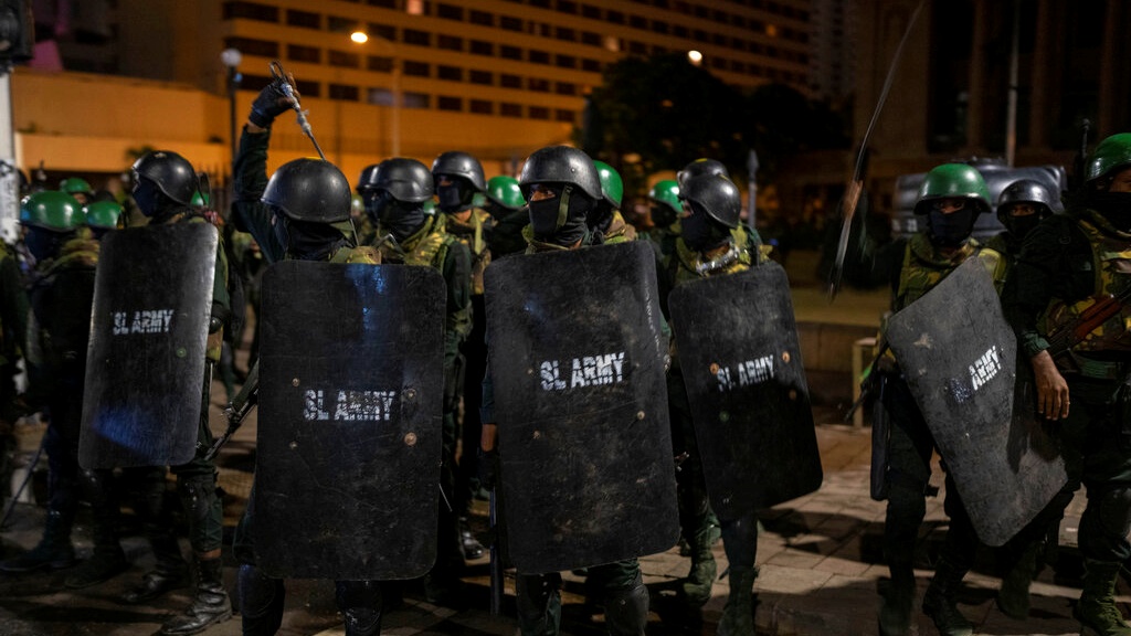 部分人員手持警棍及步槍，進逼堵塞通往總統府街道的示威者。AP圖片