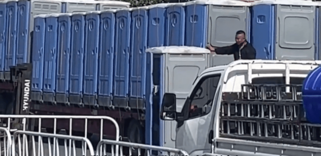 當剷車駛開時,一流動厠所的門打開了。 當剷車駛開時,一流動厠所的門打開了。