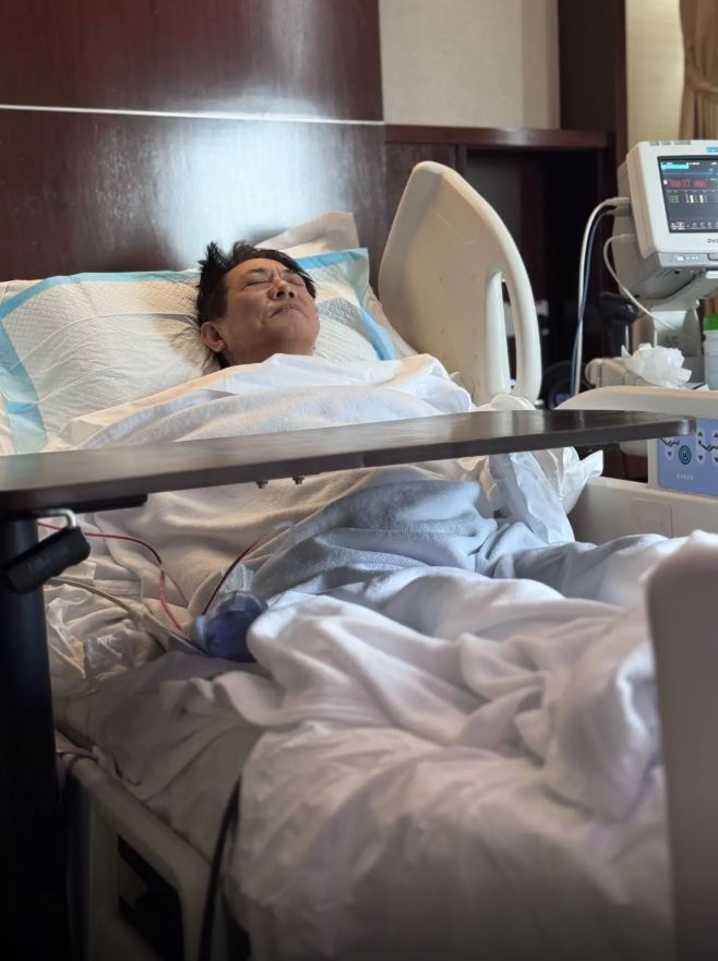 李連杰躺在病床雙眼緊閉，露出痛苦神情。